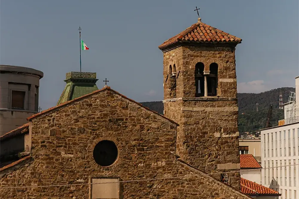 Kyrka i sten med klocktorn och tegeltak i en italiensk stad